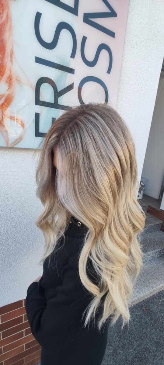 Mittellanger Stufenschnitt mit blondem Farbverlauf und lockerem Wellenstyling