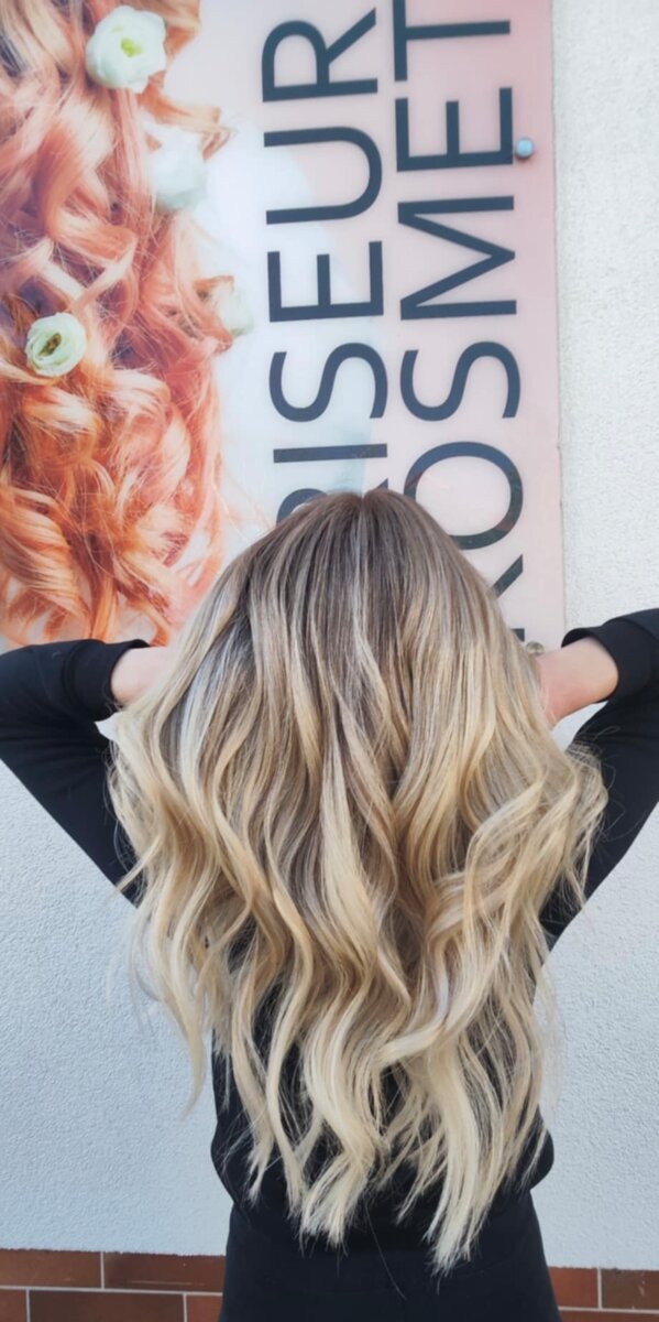 Langer, stufiger Haarschnitt mit blondem Balayage und sanften Wellen