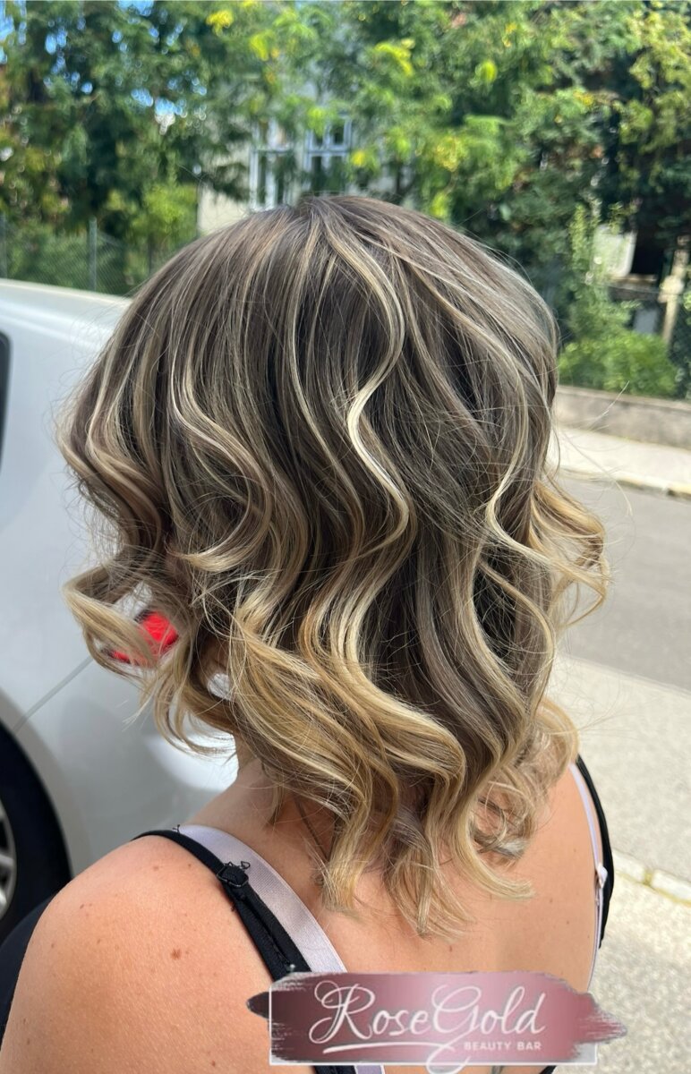 Schulterlanger Stufenschnitt mit blonden Strähnen und lockigem Styling
