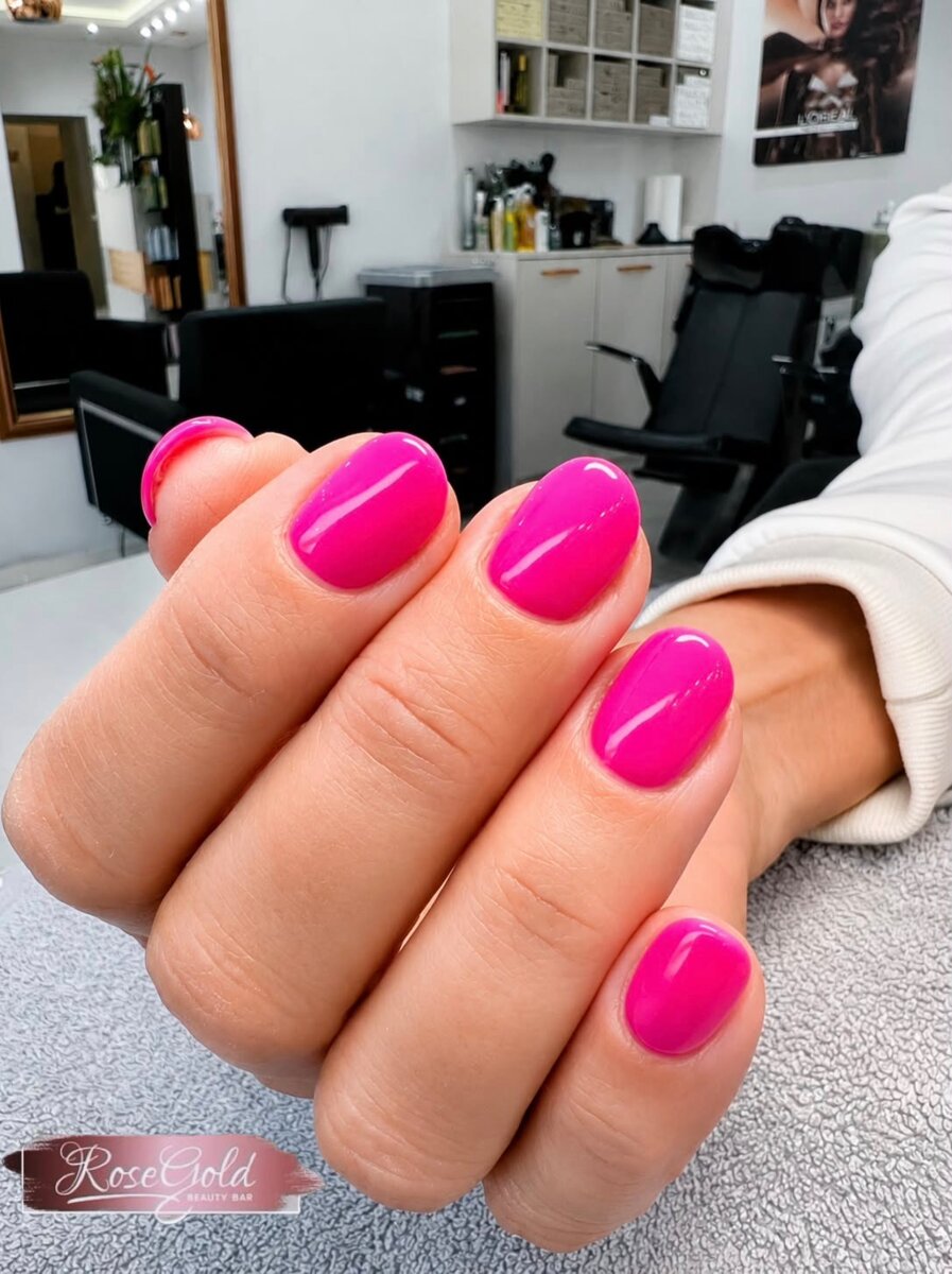 Kurze, glänzend pink lackierte Nägel nach einer professionellen Maniküre